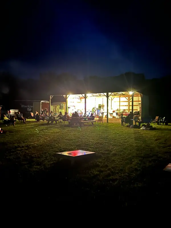 The pavilion lit up at night with people gathered on the lawn