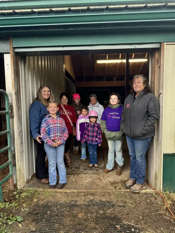 A group of adults and children standing in the open barn doorway