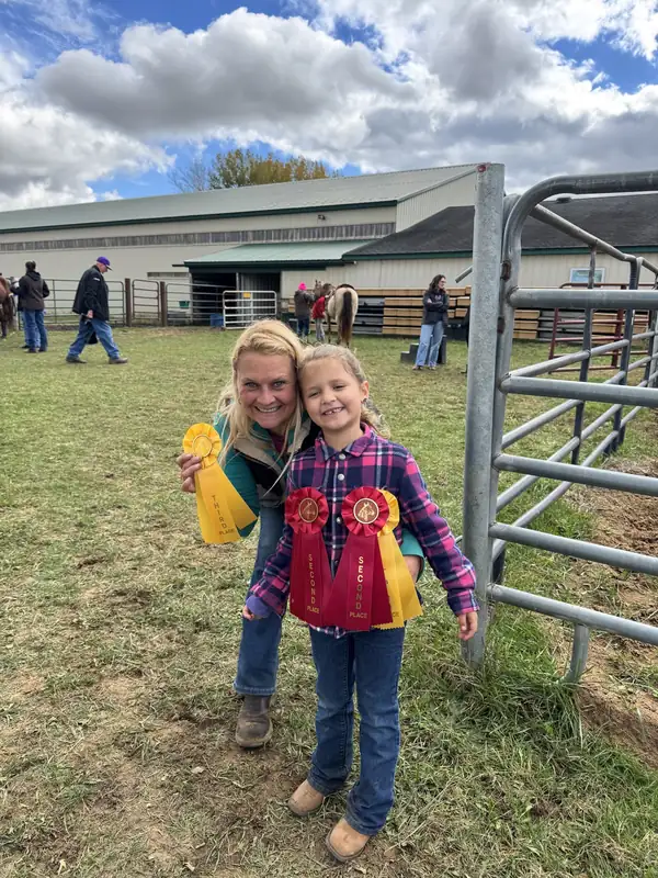 Two girls holding show ribbons beside the arena gate